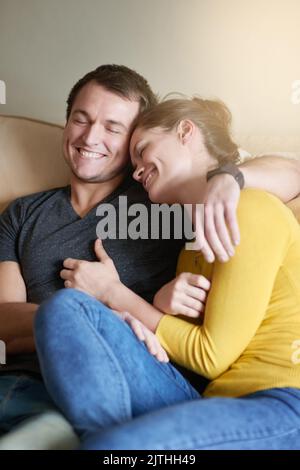 Im viel mehr ich, wenn ich mit dir bin. Ein liebevolles Paar, das sich zu Hause auf der Couch kuschelt. Stockfoto