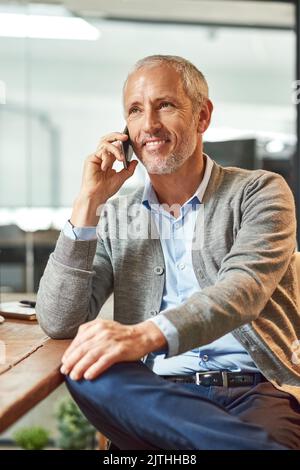 Kontakt zu neuen Kunden. Ein reifer Geschäftsmann spricht am Telefon, während er an seinem Schreibtisch in einem Büro sitzt. Stockfoto