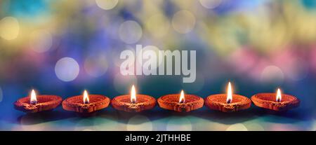 Diwali-Feier. Deepavali hinduistisches Lichterfest. Tondiyas Kerzen in einer Reihe. Öllampen leuchten auf blauem Hintergrund Stockfoto