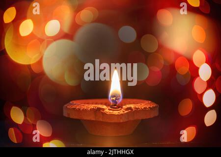 Deepavali Hindu Festival der Lichter Feier. Frohes Diwali. Diya-Lampe beleuchtet, bunte Rangoli, dunkler Bokeh heller Hintergrund. Stockfoto