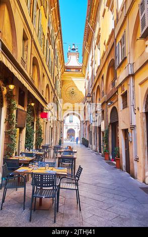 Die schmale Gasse der Via Cesare Beccaria, gesäumt von historischen Gebäuden und mit Blick auf mittelalterliche astronomische Uhr und Restaurants im Freien, Brescia Stockfoto