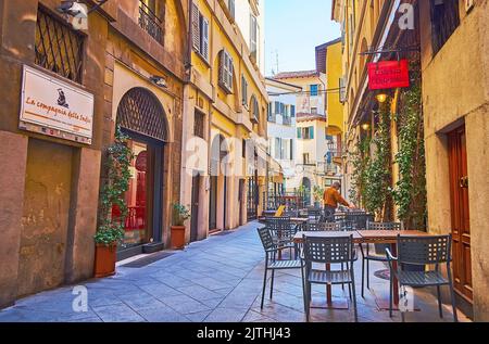 BRESCIA, ITALIEN - 10. APRIL 2022: Die schmale Via Cesare Beccaria mit alten Häusern und Straßencafés und Restaurants, am 10. April in Brescia Stockfoto