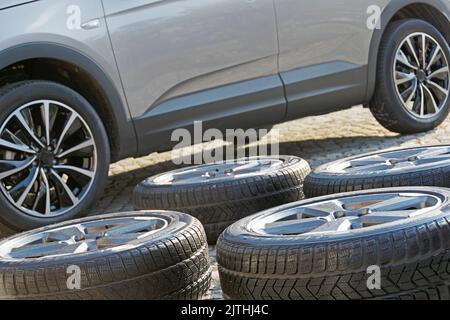 Gewaschene Winterräder vor einem modernen Auto mit Sommerrädern Stockfoto