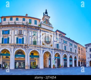 BRESCIA, ITALIEN - 10. APRIL 2022: Spaziergang auf der mittelalterlichen Piazza della Loggia mit Blick auf den Turm Torre dell'Orologio mit historischen astronomischen Stockfoto