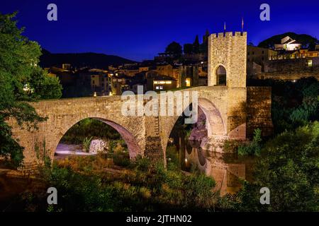 Mittelalterliche Brücke, die den Fluss in der alten Stadt Besalu bei Nacht, Gerona, Spanien überquert. Stockfoto