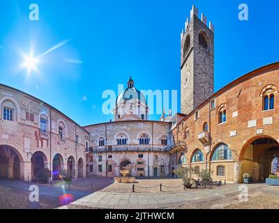 Panoramablick auf den Palazzo Broletto Hof mit Torre del pegol Uhrturm, Steinbrunnen und Kuppel der Neuen Kathedrale im Hintergrund, Brescia, Italien Stockfoto