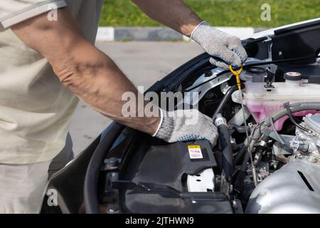 Ein Mann überprüft den Ölstand in einem Automotor Stockfoto