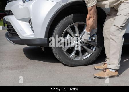 Mann, der eine Schraube an einem Autorad festzieht Stockfoto