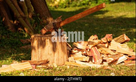 Gehacktes Brennholz neben einem Holzdeck mit einer alten Axt Stockfoto