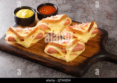 Sandwiches mit Ei, Würstchen und Toast Käse in einer Pfanne in der Nähe in der Holzplatte auf dem Tisch gebraten. Horizontal Stockfoto