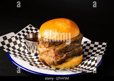 Rinderripp-Burger auf einem weißen Teller auf schwarzem Hintergrund Stockfoto
