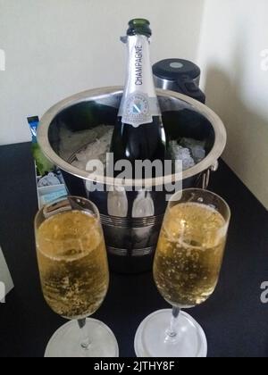 Eine Flasche Champagner in einem Eimer Eis mit Sektgläsern in einem Hotelzimmer. Stockfoto