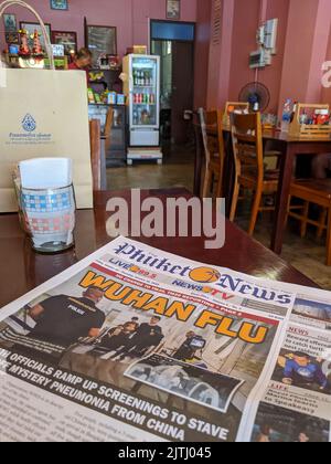 Phuket News auf einem Tisch in einem Restaurant mit der Überschrift „Wuhan Flu“ im Februar 2020, als die COVID-19-Pandemie in Kraft tritt. Stockfoto