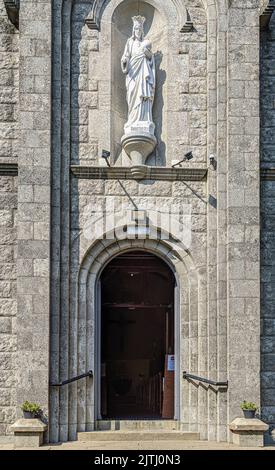 Eingang zu einer römisch-katholischen Kirche mit einer Statue von Jesus über der Tür, Nordirland. Stockfoto