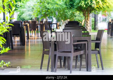 Tische und Stühle im Freien, leerer Tisch im Strandrestaurant. Möbel im Rattanstil im Restaurant Stockfoto