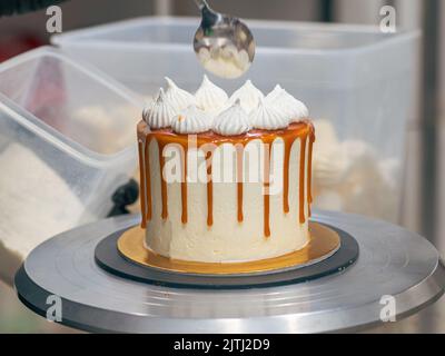 Professioneller Bäcker, der eine Schokolade und einen Sahnetorte mit salzigem Karamell dekoriert Stockfoto
