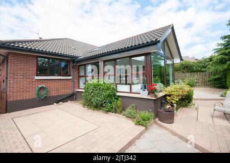 Erweiterung der Sonnenterrasse auf einen modernen Bungalow mit einer wartungsarmen Terrasse im hinteren Garten. Stockfoto