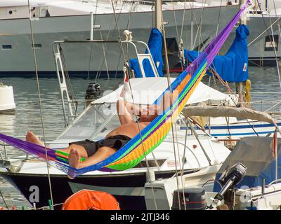 Ein Mann schläft auf einer Hängematte an Bord einer Yacht in der Marina von Monte-Carlo. Stockfoto