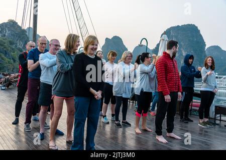 Halong Bay, Vietnam. 9.. Februar 2018. Touristen auf einem Schiff besuchen eine Tai-Chi-Sitzung bei Sonnenaufgang auf dem Deck. Stockfoto