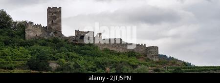 SPITZ, ÖSTERREICH - 13. JULI 2019: Panoramablick auf die Ruinen von Schloss Hinterhaus auf den bewaldeten Hügeln über der Stadt Stockfoto