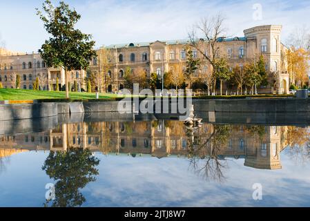 Taschkent, Usbekistan. November 2021. Das Gebäude in der Nähe des Amir Timur Platzes spiegelt sich in der Wasseroberfläche wider Stockfoto