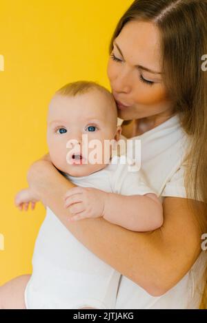 Die fürsorgliche Mutter hält ihren kleinen Sohn in den Armen und küsst ihn Stockfoto