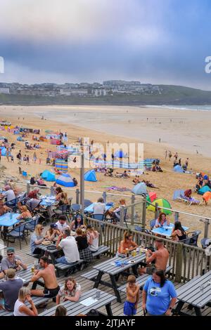 An einem der heißesten Tage des Jahres in Großbritannien genossen Urlauber am Fistral Beach den warmen, nebligen Sonnenschein und die willkommene, kühle Meeresbrise auf dem See Stockfoto