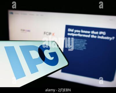 Handy mit Logo der Interpublic Group of Companies Inc. (IPG) auf dem Bildschirm vor der Business-Website. Konzentrieren Sie sich auf die Mitte links des Telefondisplays. Stockfoto