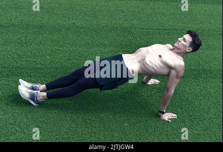 Die umgekehrte Plank stärkt den unteren Rücken und den Mann beim Training im Freien Stockfoto