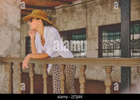 Frau mit Cowboyhut auf der Veranda sitzend, Jalisco Mexiko, Porträt einer glücklichen Frau mit Hut. Selektiver Fokus. Stockfoto
