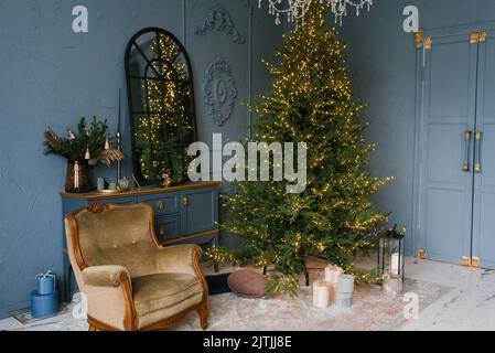 Weihnachten und Neujahr schmücken das dunkle Innere des Raumes. Ein festlich eingerichtetes Zimmer mit Kamin, Sessel und Spiegel. Festliche Christma Stockfoto