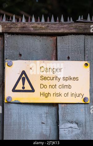 Sicherheitsspitzen und Warnhinweise an einem Zaun in Cardiff, Wales, Großbritannien Stockfoto