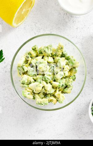 Avocado Eier Salat in Glas Schüssel auf hellem Stein Hintergrund. Draufsicht, flach liegend Stockfoto