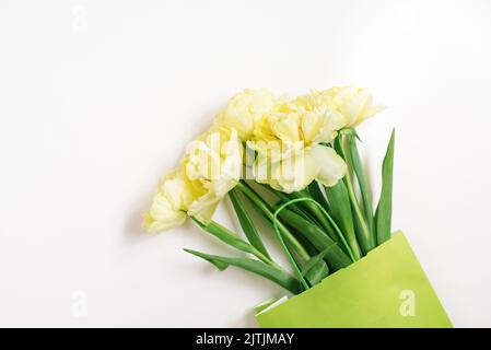 Nachbildung einer Einkaufstasche aus Papier mit Tulpenblumen auf weißem Hintergrund. Osterangebot im Frühling. Das Konzept der Umweltfreundlichkeit und die Stockfoto