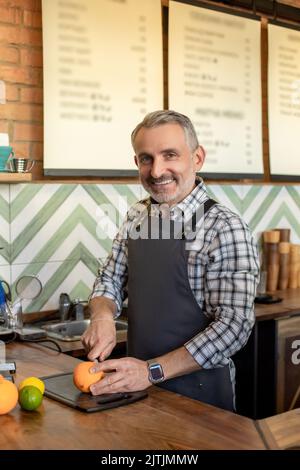 Professioneller Barista, der ein frisches Zitrusgetränk für einen Gast zubereitet Stockfoto