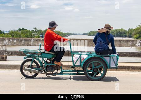 Zwei Männer fahren mit einem Wagen auf einer Brücke ein Dreirad Stockfoto