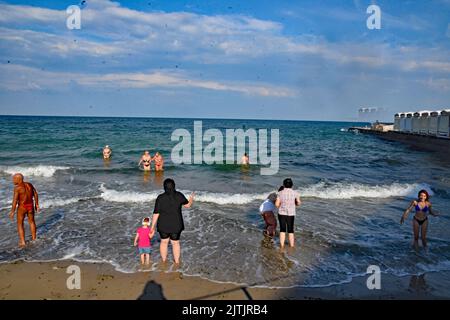 Odessa, Ukraine. 10. August 2022. Im August 2022 gehen Menschen in Odessa, Ukraine, an einem Strand mit Warnschildern schwimmen, die darauf hinweisen, dass es sich um meine Sünde im Wasser handelt. Odessa war ein beliebter Touristenort zum Schwimmen und einen Tag am Strand vor der russischen Invasion. Jetzt schwimmen die Menschen auf eigenes Risiko, da Minen angelegt wurden, um sich gegen Vorstöße des russischen Militärs aus dem Schwarzen Meer zu verteidigen. (Foto: Teun Voeten/Sipa USA) Quelle: SIPA USA/Alamy Live News Stockfoto