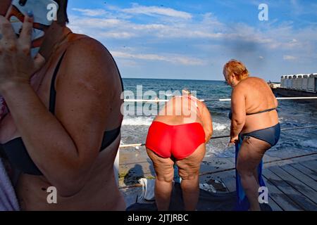 Odessa, Ukraine. 10. August 2022. Im August 2022 gehen Menschen in Odessa, Ukraine, an einem Strand mit Warnschildern schwimmen, die darauf hinweisen, dass es sich um meine Sünde im Wasser handelt. Odessa war ein beliebter Touristenort zum Schwimmen und einen Tag am Strand vor der russischen Invasion. Jetzt schwimmen die Menschen auf eigenes Risiko, da Minen angelegt wurden, um sich gegen Vorstöße des russischen Militärs aus dem Schwarzen Meer zu verteidigen. (Foto: Teun Voeten/Sipa USA) Quelle: SIPA USA/Alamy Live News Stockfoto