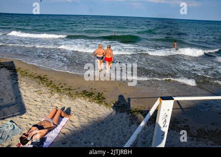 Odessa, Ukraine. 10. August 2022. Im August 2022 gehen Menschen in Odessa, Ukraine, an einem Strand mit Warnschildern schwimmen, die darauf hinweisen, dass es sich um meine Sünde im Wasser handelt. Odessa war ein beliebter Touristenort zum Schwimmen und einen Tag am Strand vor der russischen Invasion. Jetzt schwimmen die Menschen auf eigenes Risiko, da Minen angelegt wurden, um sich gegen Vorstöße des russischen Militärs aus dem Schwarzen Meer zu verteidigen. (Foto: Teun Voeten/Sipa USA) Quelle: SIPA USA/Alamy Live News Stockfoto