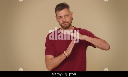 Auszeit, eine Pause nötig. Müde ernst verärgert schöner junger Mann in rotem T-Shirt zeigt Pause entspannen Geste, Grenze oder Stopp-Zeichen. Erwachsene stilvolle männlichen Kerl isoliert allein auf beige Studio Hintergrund drinnen Stockfoto