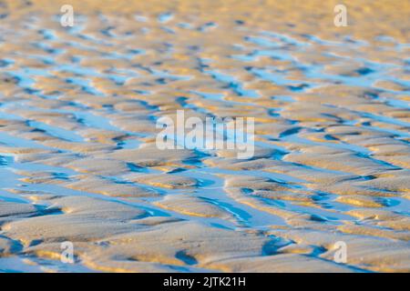 Typischer Blick auf die Küste nach der Flut, mit dem salzigen Wasser, das erstaunliche Muster am Strand hinterlässt, während das Wasser einen Weg zurück findet Stockfoto