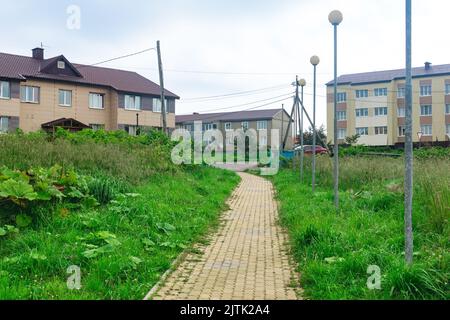 Straße im Dorf Juschno-Kurilsk auf der Insel Kunaschir mit zweistöckigen Holzhäusern Stockfoto