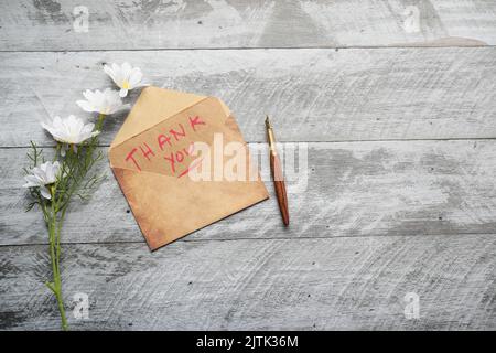 Dankesnachricht und Umschlag auf Holztisch Stockfoto