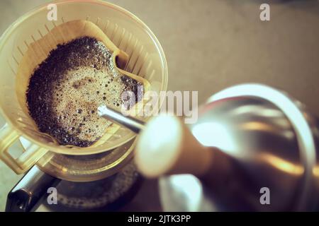 Kaffee im Vintage-Stil am Morgen. Nahaufnahme von gemahlenem Kaffee in einem Tropf, während Aroma-Espresso zubereitet wird. Stockfoto