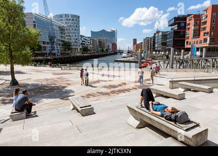 In der Sommersonne liegen und sitzen die Menschen auf den Magellan-Terrassen und blicken auf die Elbphilharmonie und die Hamburger HafenCity, Hamburg, Deutschland Stockfoto