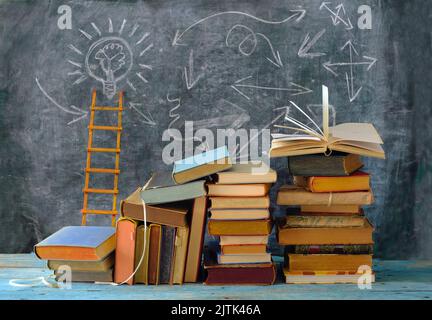 Bildung gibt Orientierung, Bücher, Tafel und Leiter des Erfolgs.Lernen, Wissen, Humanismus, zurück zur Schule Konzept Stockfoto