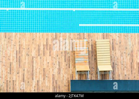 Minimalistischer Stil, Blick von oben auf den Swimmingpool mit Holzboden und Stuhl, blaue Fliesen mit weißer Linie Stockfoto