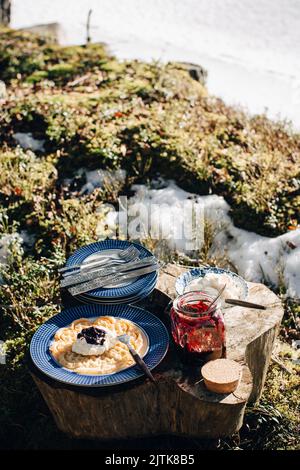 Pfannkuchen auf dem Teller serviert, der während eines sonnigen Tages von Eingemachtes auf dem Holztafel aufbewahrt wird Stockfoto