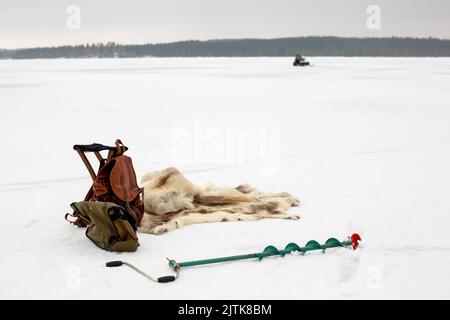 Rucksack von Tierhaut und Eisschnecke auf Schnee im Winter gehalten Stockfoto