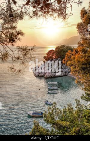 Herrlicher Strand mit Booten gegen Sonnenuntergang in Brela, Makarska, Dalmatien, Kroatien Stockfoto